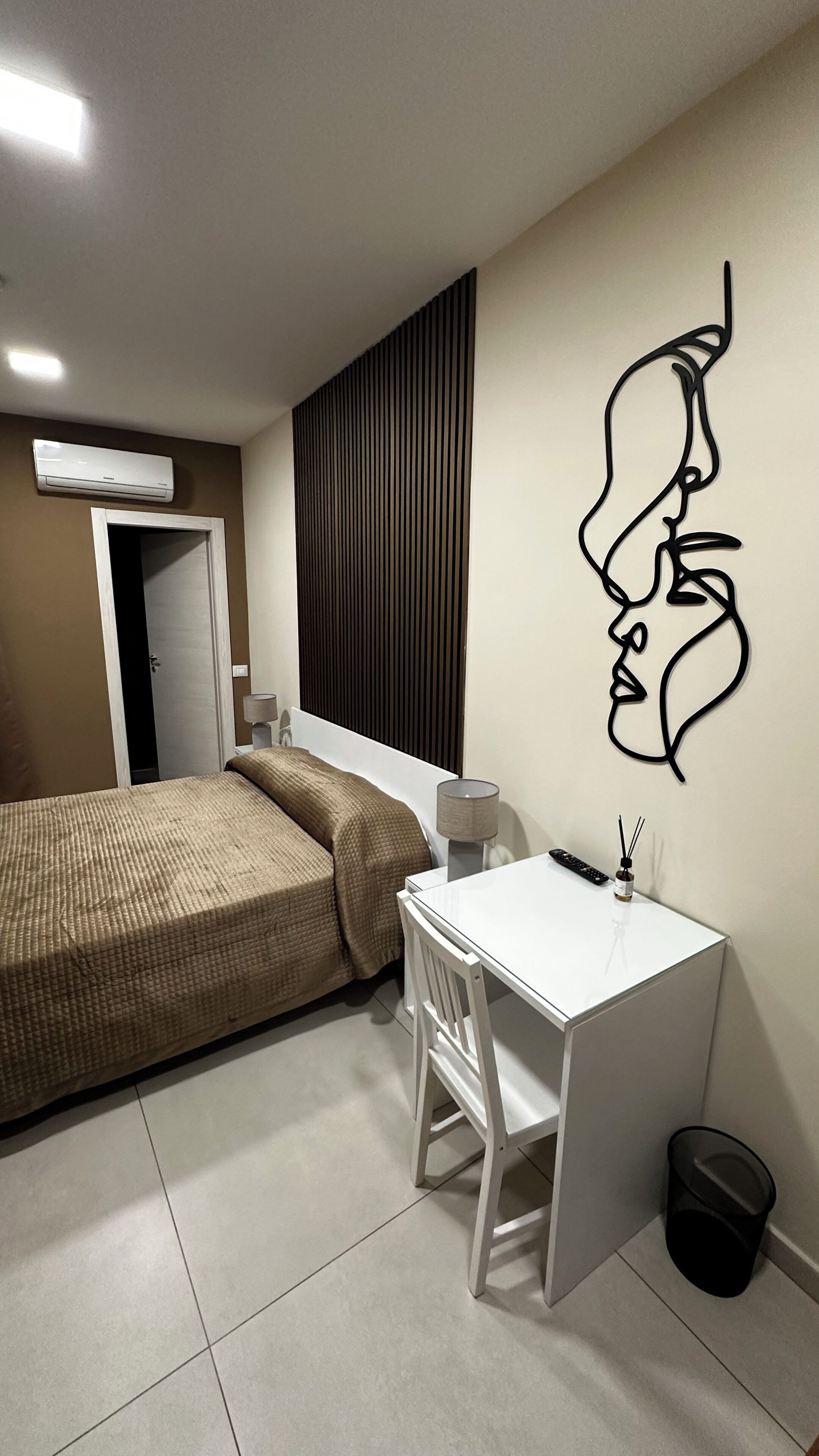 Un dormitorio con cama, escritorio y una obra de arte colgada en la pared.