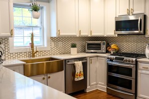 Una cocina moderna con electrodomésticos de acero inoxidable, un microondas, un tostador y un lavamanos.