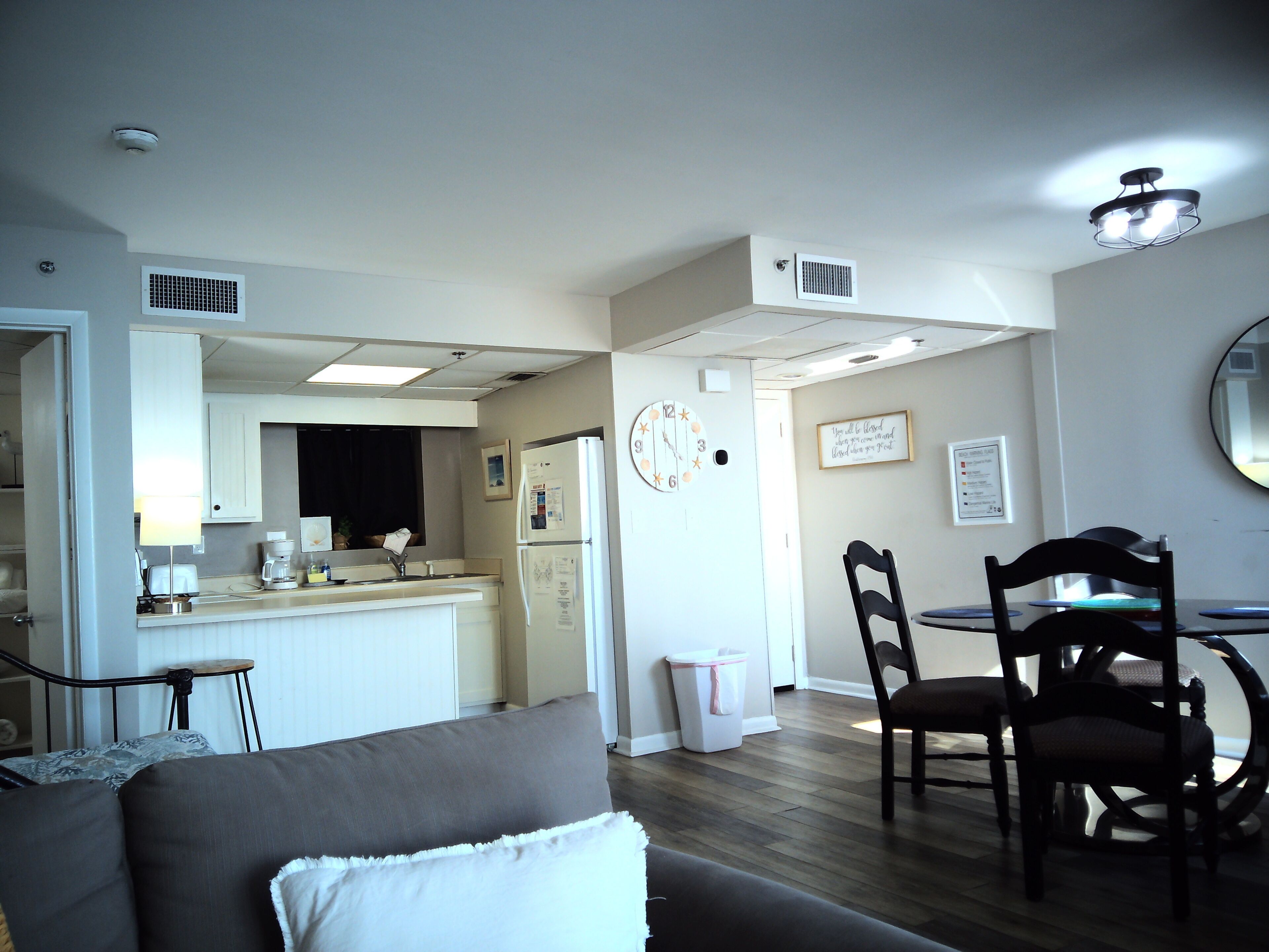 A modern kitchen with a refrigerator, microwave, and coffee maker. There is a dining area with a table and chairs.
