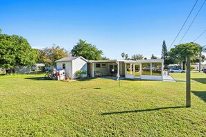 A single-story house with a covered porch and a small detached garage. - Beautiful Home in Vero Beach, 5 Min to Beach, Sleeps 6, King Bed (Vero Beach)
