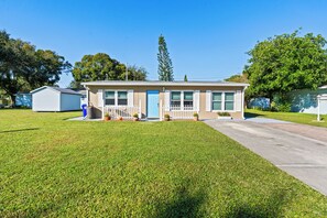 A single-story mobile home with a front porch, a small attached garage, and a well-maintained lawn. - Beautiful Home in Vero Beach, 5 Min to Beach, Sleeps 6, King Bed (Vero Beach)