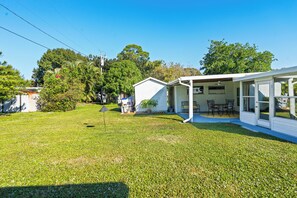 Une maison blanche avec un patio couvert et une pelouse.