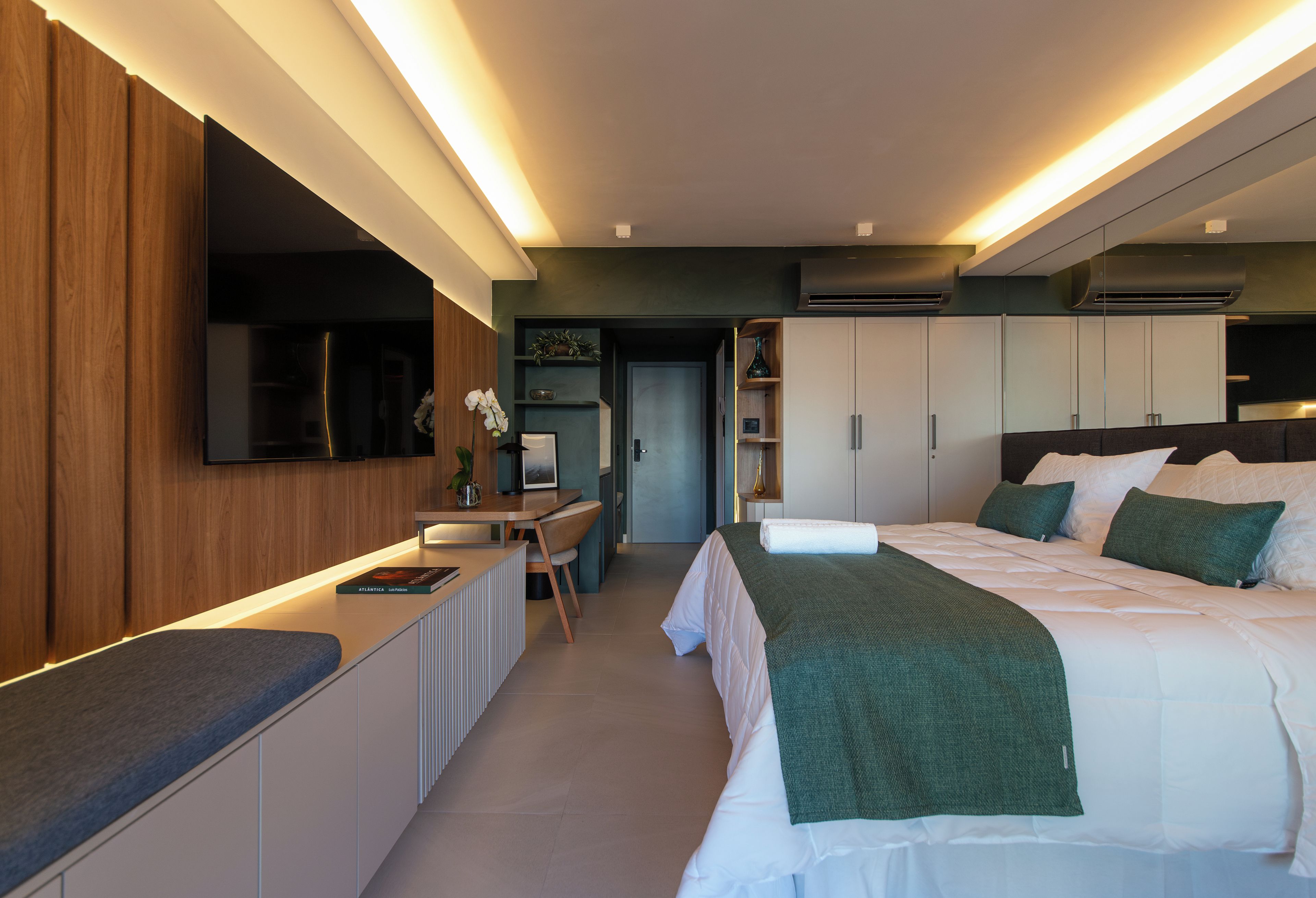 Ein modernes Hotelzimmer mit Bett, Nachttischen, Schreibtisch und Kleiderschrank.