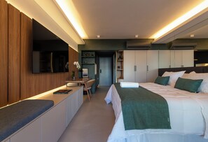 Una habitación de hotel moderna con cama, mesitas de noche, un escritorio y un armario.