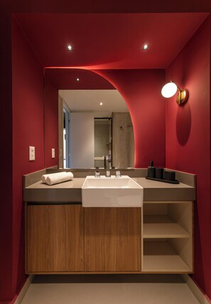 Een moderne badkamer met een grote spiegel, een witte wastafel en een houten wastafelmeubel.