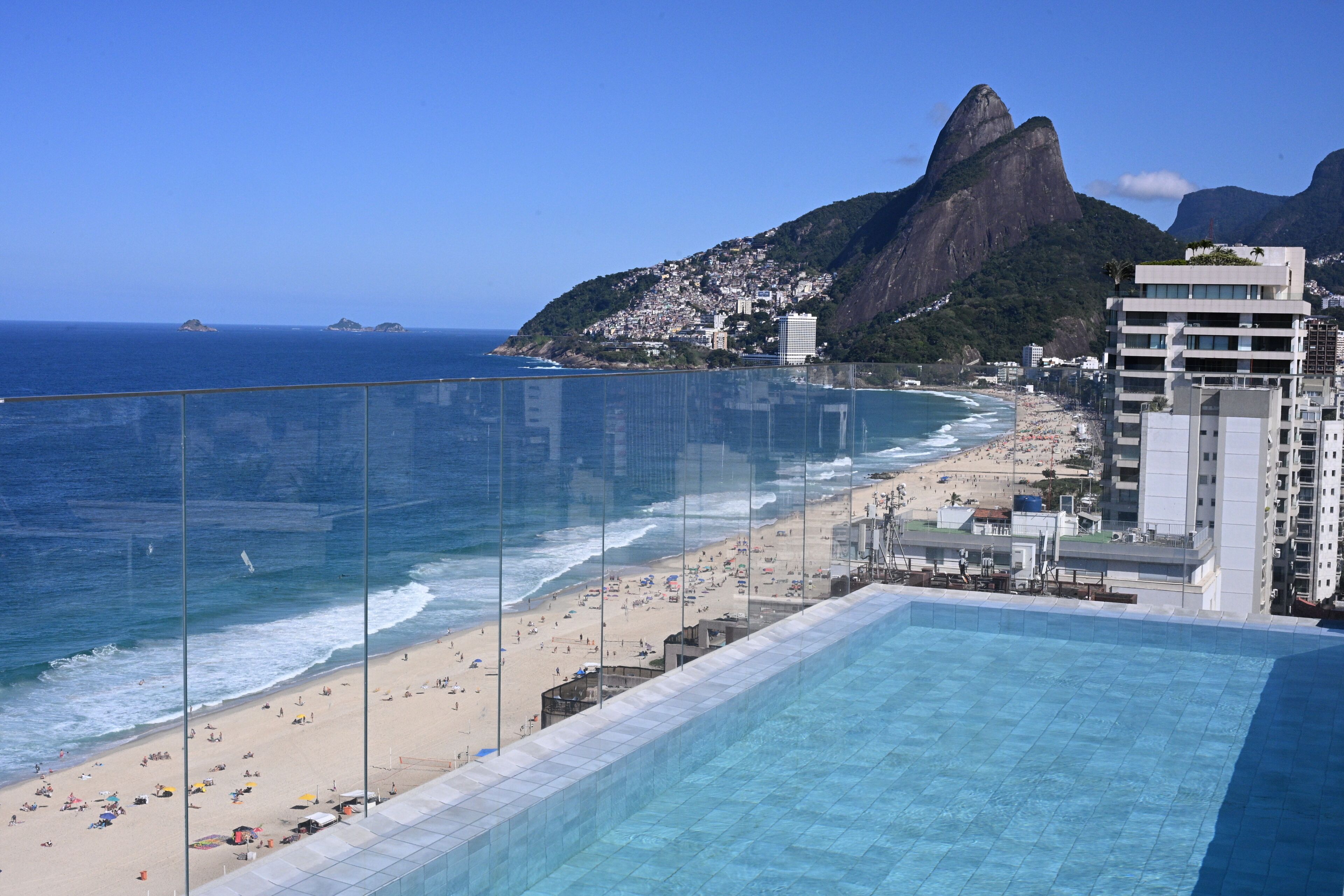 A coastal hotel with a pool, beach, and mountain views.