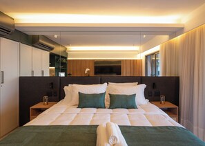 Een moderne hotelkamer met een groot bed, een flatscreen televisie aan de muur en een houten hoofdeinde.