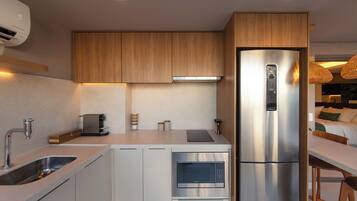 Una cocina moderna con microondas integrado, cafetera y refrigerador.