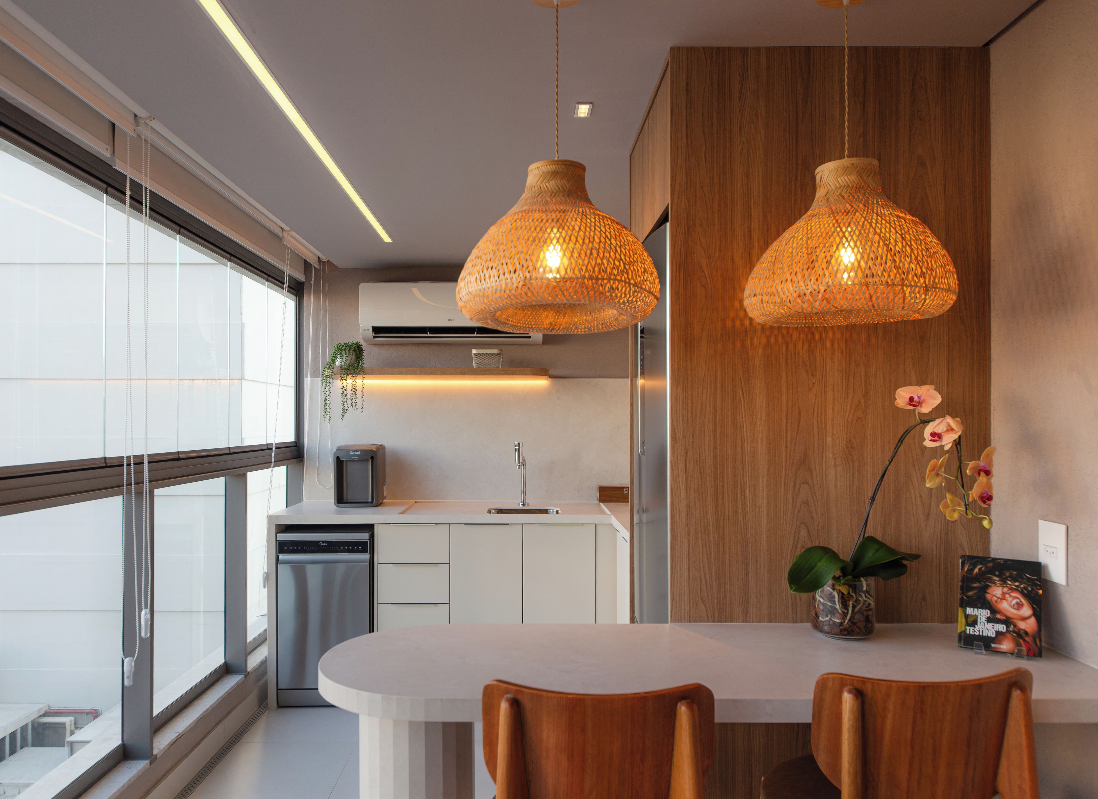 Une cuisine moderne dotée d’un îlot central, de luminaires suspendus et offrant une vue sur la ville.