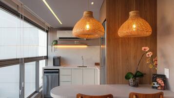 Une cuisine moderne dotée d’un îlot central, de luminaires suspendus et offrant une vue sur la ville.