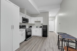 A modern kitchen with white cabinets, a black refrigerator, a microwave, and a stove.