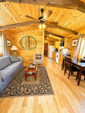 Un intérieur de chalet chaleureux comprenant un salon, un coin repas et une cuisine.