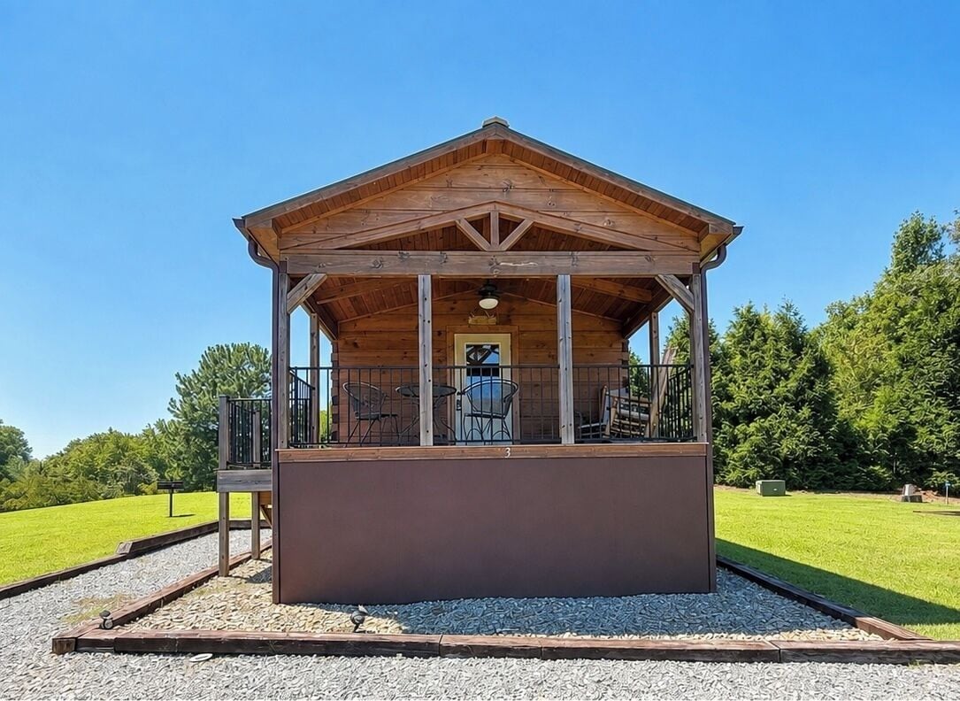 Une cabane en bois avec un balcon, une petite table et une chaise.