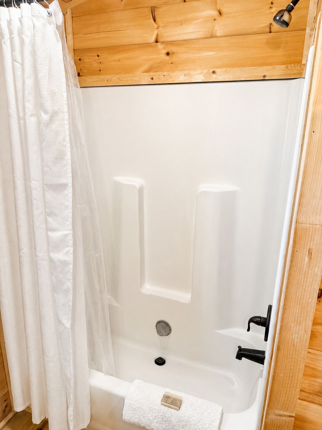 Une baignoire blanche avec un rideau de douche, un robinet et un drain.