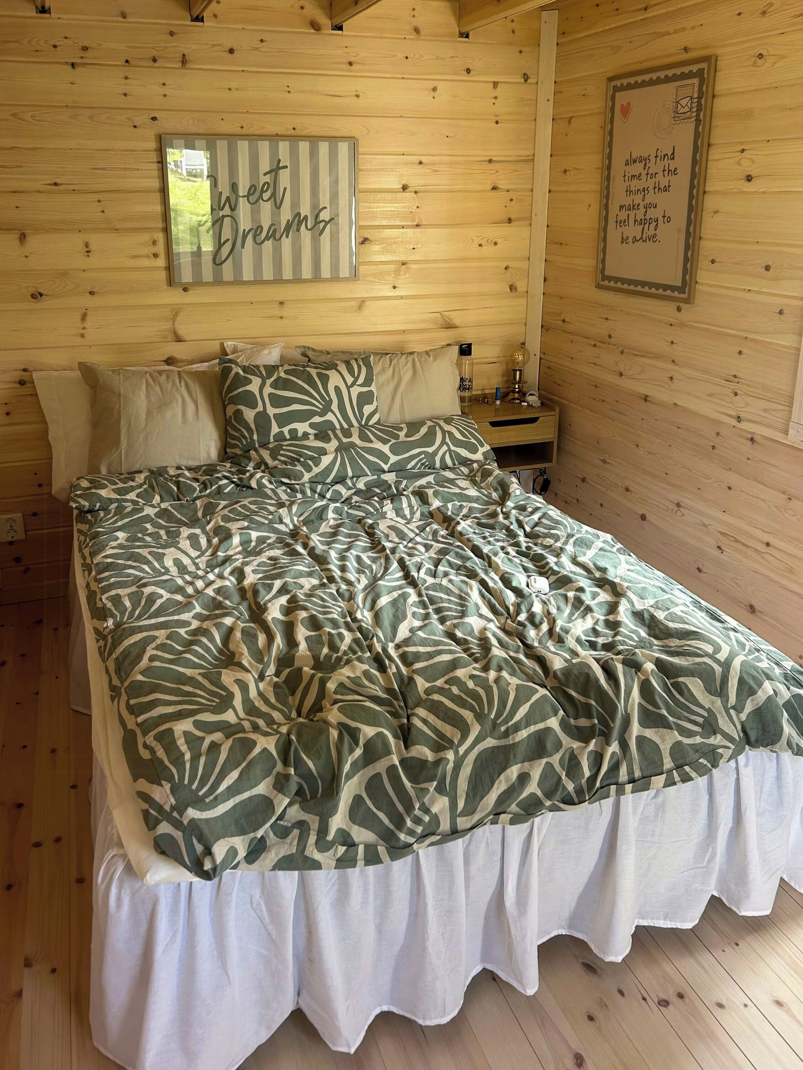 A wooden room with a bed, a nightstand, and a wall with motivational posters.