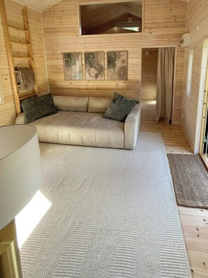A cozy cabin interior with a sofa, a lamp, and artwork on the walls. - Country retreat on Håtö near sea and fishing (Stockholms län)