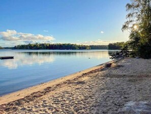 Ein ruhiger See mit einem Sandstrand und einer Anlegestelle.