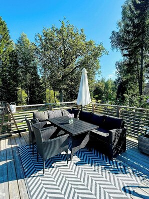 An outdoor deck with a dining table and chairs, surrounded by a wooden deck and trees. - Country retreat on Håtö near sea and fishing (Stockholms län)