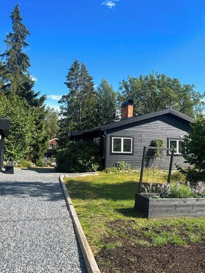A residential property with a gravel driveway, a wooden deck, and a well-maintained lawn. - Country retreat on Håtö near sea and fishing (Stockholms län)