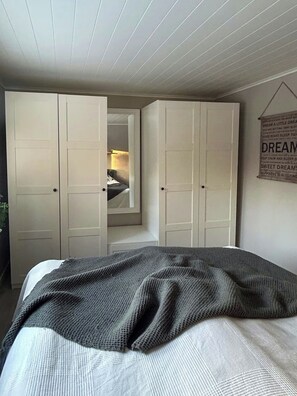 A bedroom with a bed, a wardrobe, and a door leading to a bathroom. - Country retreat on Håtö near sea and fishing (Stockholms län)