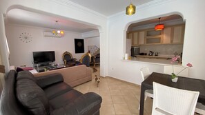 Ein Wohnzimmer mit einer schwarzen Couch, einem Fernseher und einer Wanduhr.