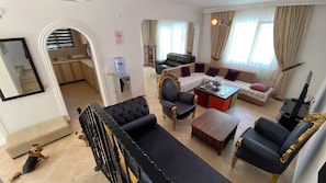 Una sala de estar con un sofá, sillones, una mesa de centro y un televisor.