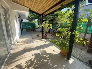 Un patio cubierto con plantas en macetas y un sendero de grava.
