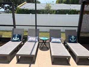 Eine Terrasse mit vier Liegestühlen, jeweils mit einem Kissen mit Anker-Motiv. Ein kleiner runder Tisch steht zwischen den Stühlen.