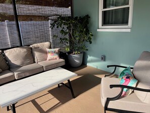 A patio with a beige sofa, a white table, and a potted plant. - 3-bedroom family friendly with pool in wonderful Largo just minutes to beaches (Largo)