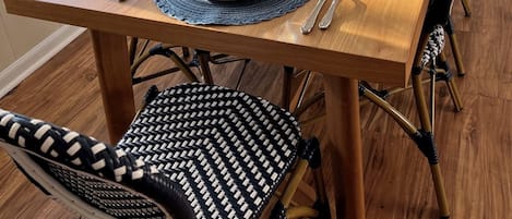 A dining table set with blue plates, silverware, and clear glasses, surrounded by black and white patterned chairs.