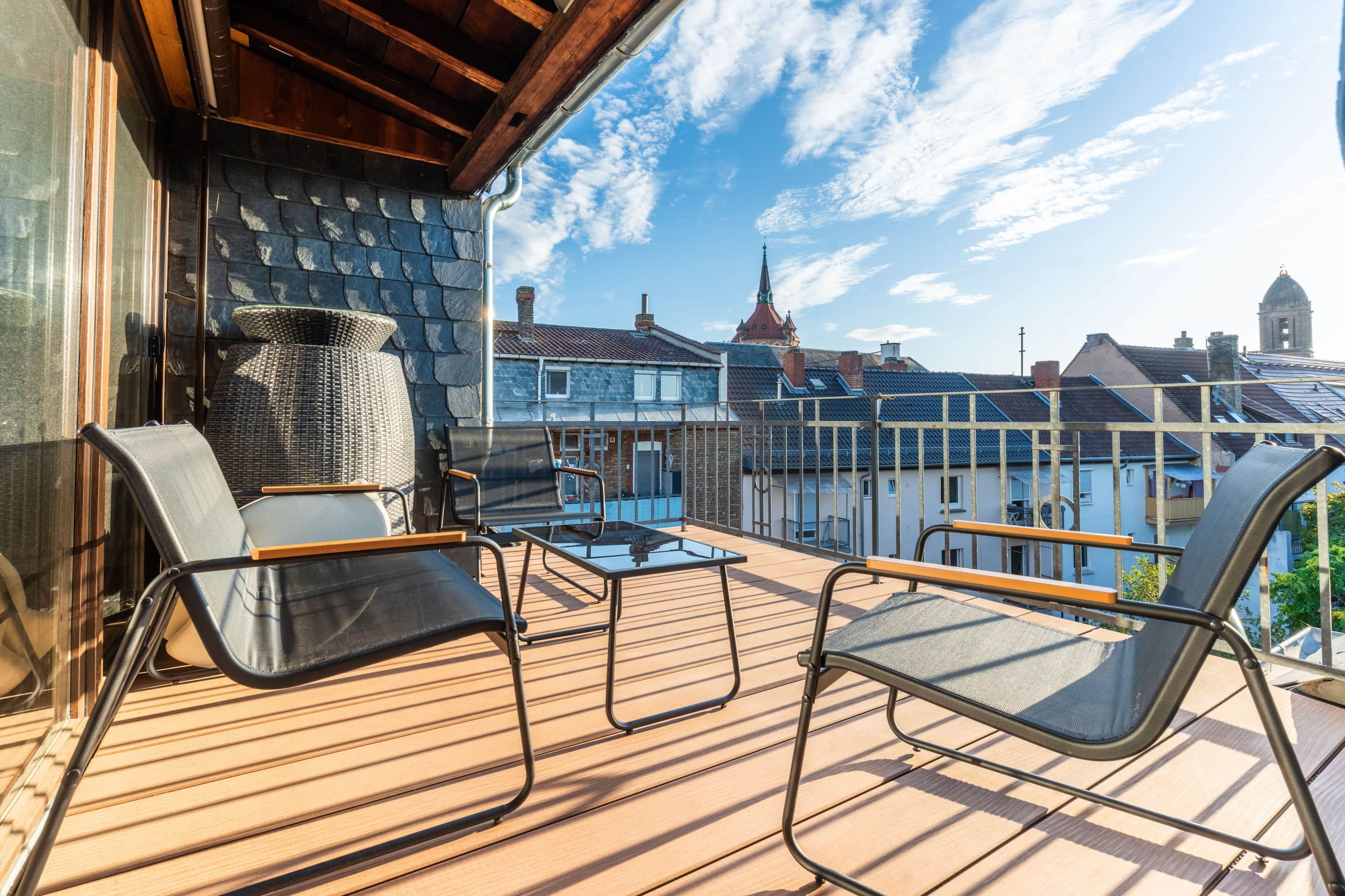 Ein Balkon mit Gartenmöbeln, Blick auf Gebäude und einem klaren Himmel.