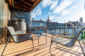 Ein Balkon mit Gartenmöbeln, Blick auf Gebäude und einem klaren Himmel.