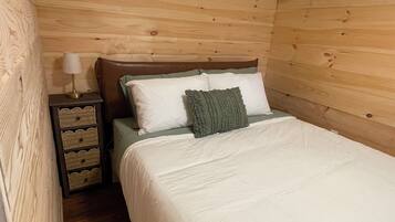 A wooden-paneled room with a bed, a nightstand, and a lamp.