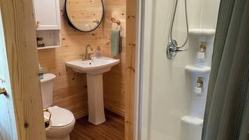 A wooden interior bathroom with a toilet, sink, and shower.