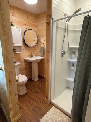 Een badkamer met houten details, voorzien van toilet, wastafel en douche.