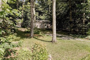 A cabin surrounded by trees with a grassy yard.