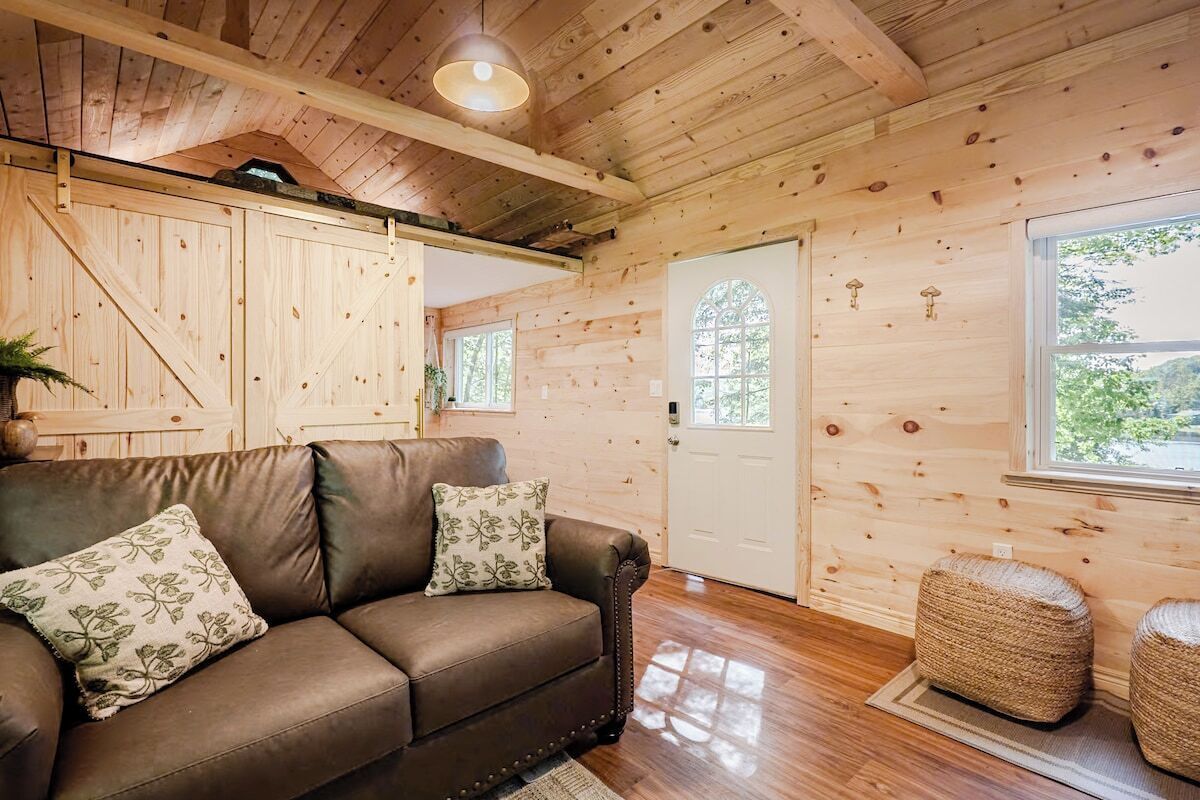 A wooden interior with a leather sofa, a door, and a window.