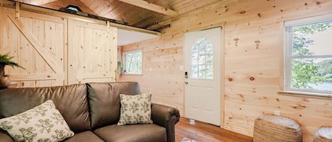 A wooden interior with a leather sofa, a door, and a window.