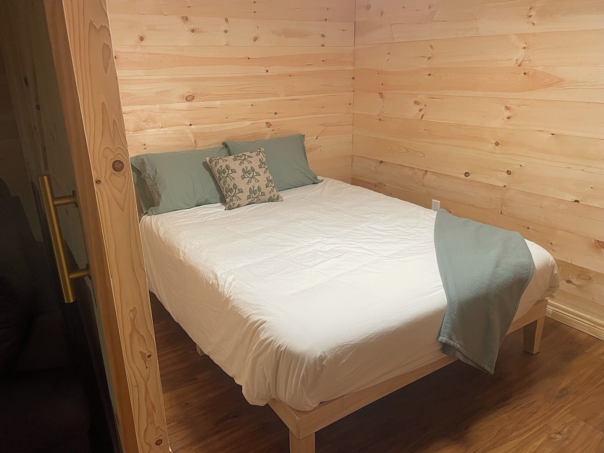 A single bed in a room with wooden walls and a wooden floor.