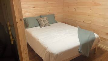 A single bed in a room with wooden walls and a wooden floor.