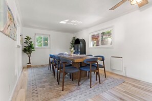 Un comedor con una mesa de madera y sillas azules, una planta en maceta y un radiador.