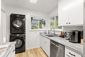 Una cocina compacta equipada con lavadora, cafetera y lavavajillas.