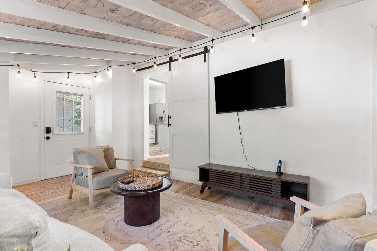 Un salon moderne avec un téléviseur à écran plat, un parquet, une table basse ronde et un canapé.