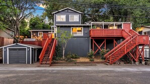 Ein zweigeschossiges Haus mit einer roten Treppe, einer Garage und einem kleinen Garten.