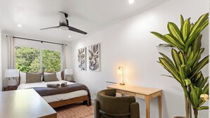 Ein Schlafzimmer mit einem Bett, Schreibtisch, Stuhl und einer großen Topfpflanze.