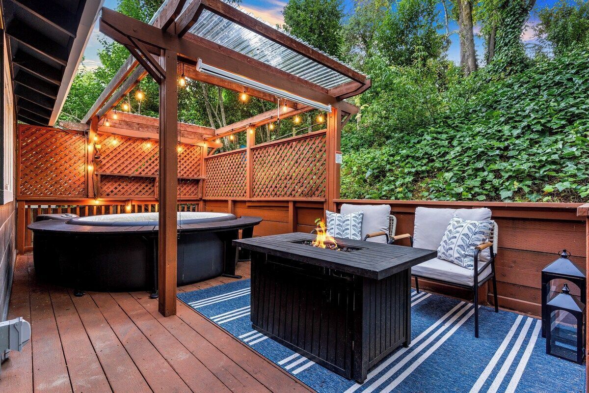 An outdoor deck with a hot tub, a fire pit, and seating area.