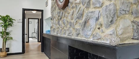 Een modern interieur met een stenen muur, een open haard met hout en een klok.