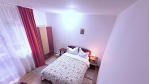 A hotel room with a bed, bedside tables, a desk, a wardrobe, and a window with curtains. - Villa Ileana  (Ceahlău)