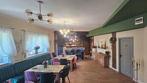A dining area with a long table, multiple chairs, and a bar area in the background.