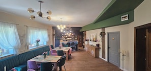 A dining area with a long table, multiple chairs, and a bar area in the background. - Villa Ileana  (Ceahlău)
